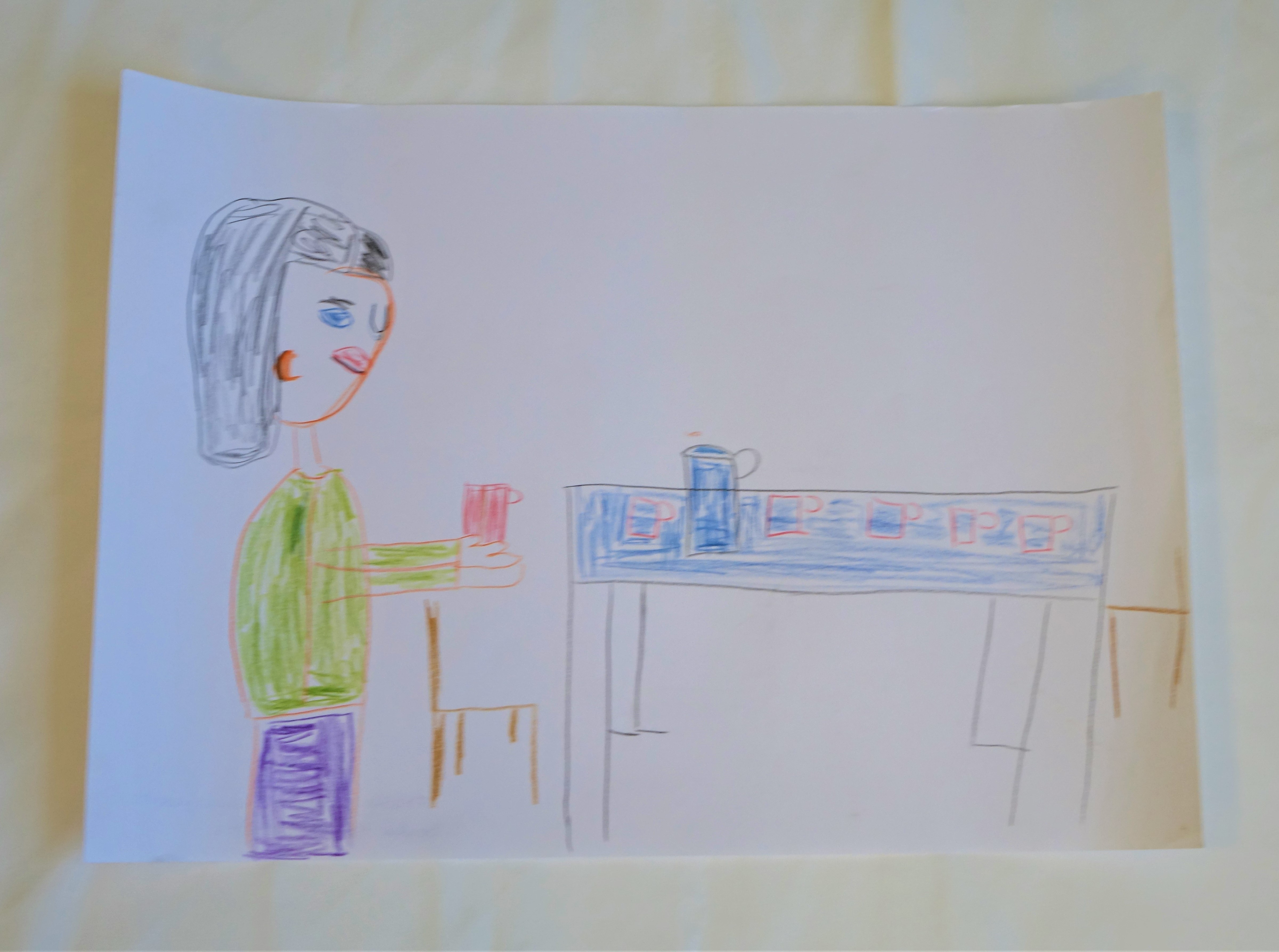 A4 méretű színes rajz. A kép bal oldalán áll Árpád. Haja hosszú fekete, szeme kék. Zöld pulóvert és lila nadrágot visel, kezében egy piros bögre. Előtte egy kék asztal két darab barna székkel. Az asztalon egy kancsó és öt darab pohár.