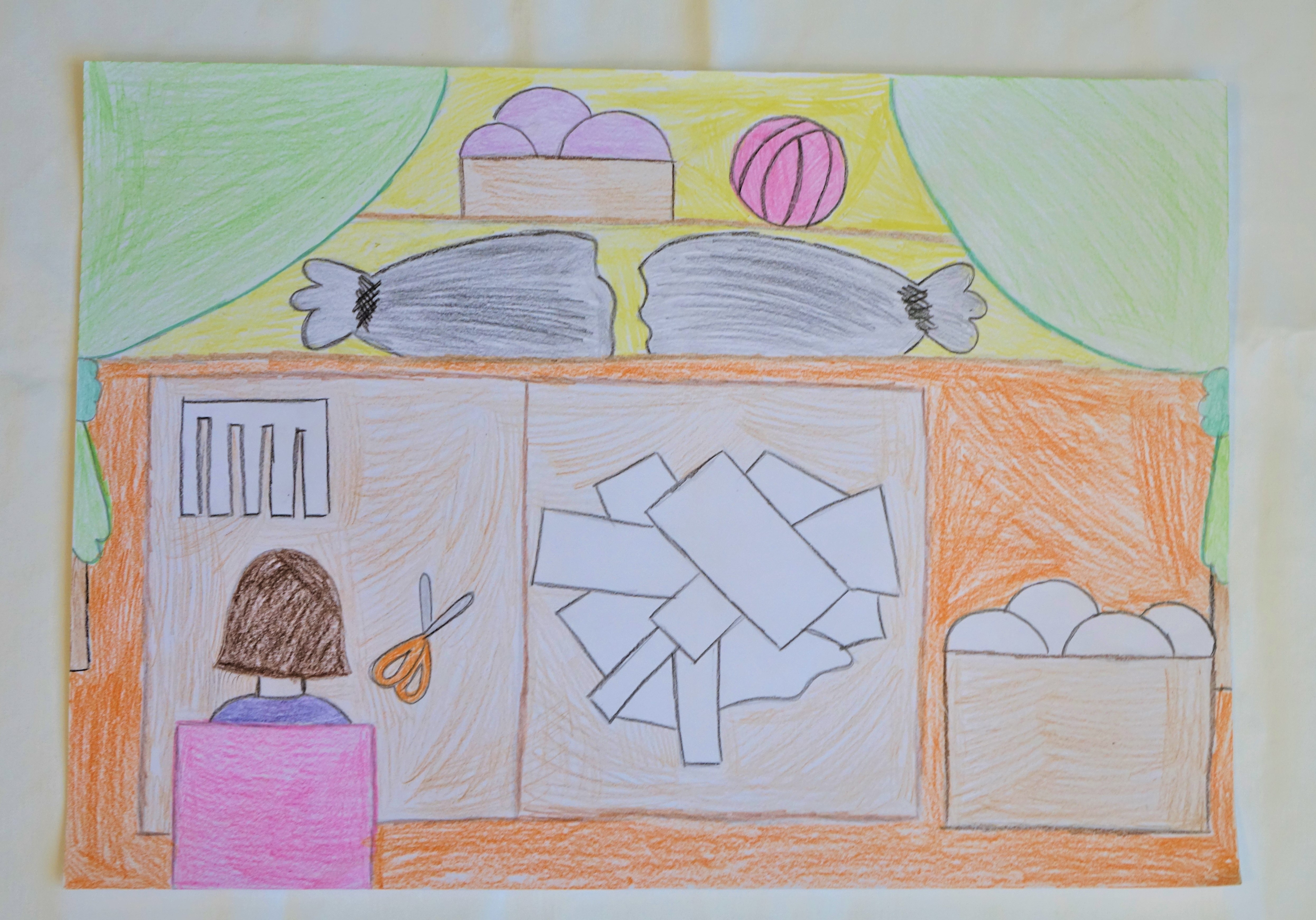 A rajz A4 méretben készült, színes ceruzával. A kép középpontjában egy barna színű asztal látható, rajta a varrodában végzett  szabás munkafolyamata látható lerajzolva. A kép bal alsó sarkában a pályázó lerajzolta magát, amint ül egy rózsaszín széken háttal, barna hajjal. A kép felső részében két oldalt zöld színű függöny látható összekötve, háttérben polc látható a varrodai alapanyagokkal, gombolyagokkal, ruhaanyagokkal.