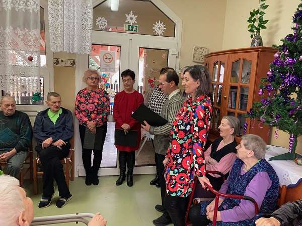 Az idősotthon lakói és a gondozók karácsonyfával az ünnepségen