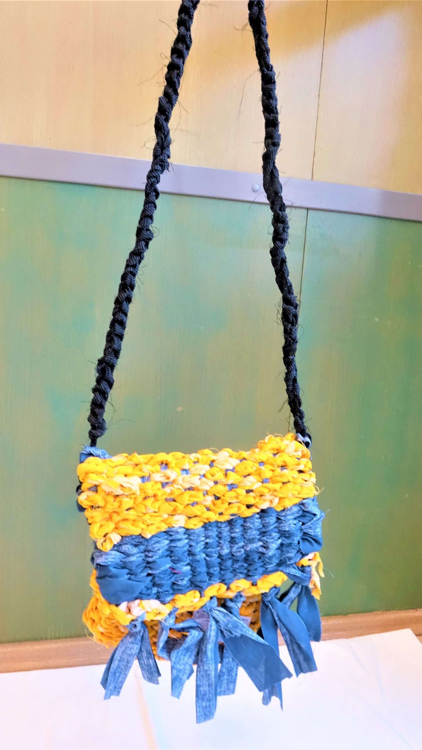 A képen egy saját készítésű szövőkereten készített sárga és kék tarisznya látható, aminek az alapanyaga horgolt textil.